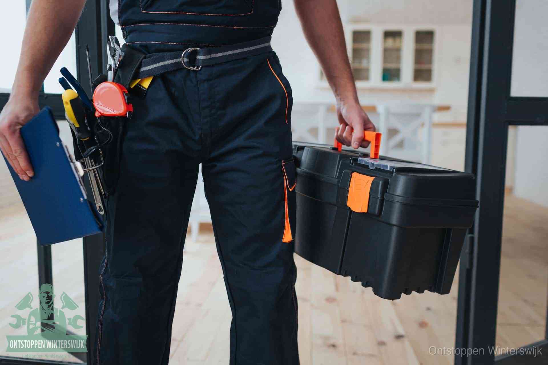 Een monteur met gereedschapsriem en klembord in een keuken, klaar om een transparante prijs voor het gootsteen ontstoppen in Winterswijk te geven
