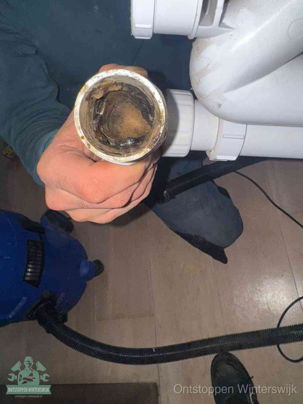 Een losgekoppelde afvoerbuis die van binnen volledig is dichtgeslibd met vet en aanslag, de meest voorkomende oorzaak van een verstopte gootsteen in Winterswijk