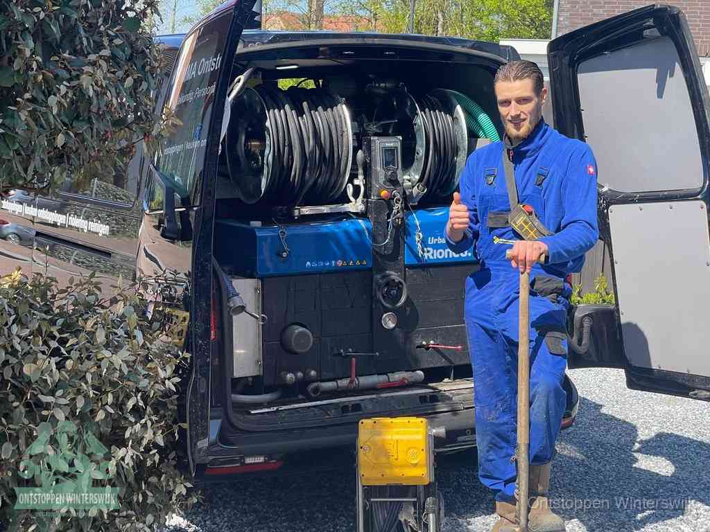 Lachende monteur bij de volle rioolreinigingsbus, een professioneel rioolontstoppingsbedrijf in Winterswijk