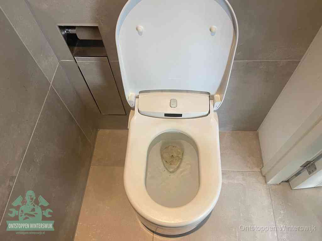 Een wit hangtoilet waarin een prop wc-papier op het water blijft drijven, een duidelijk signaal van een verstopte wc in Winterswijk
