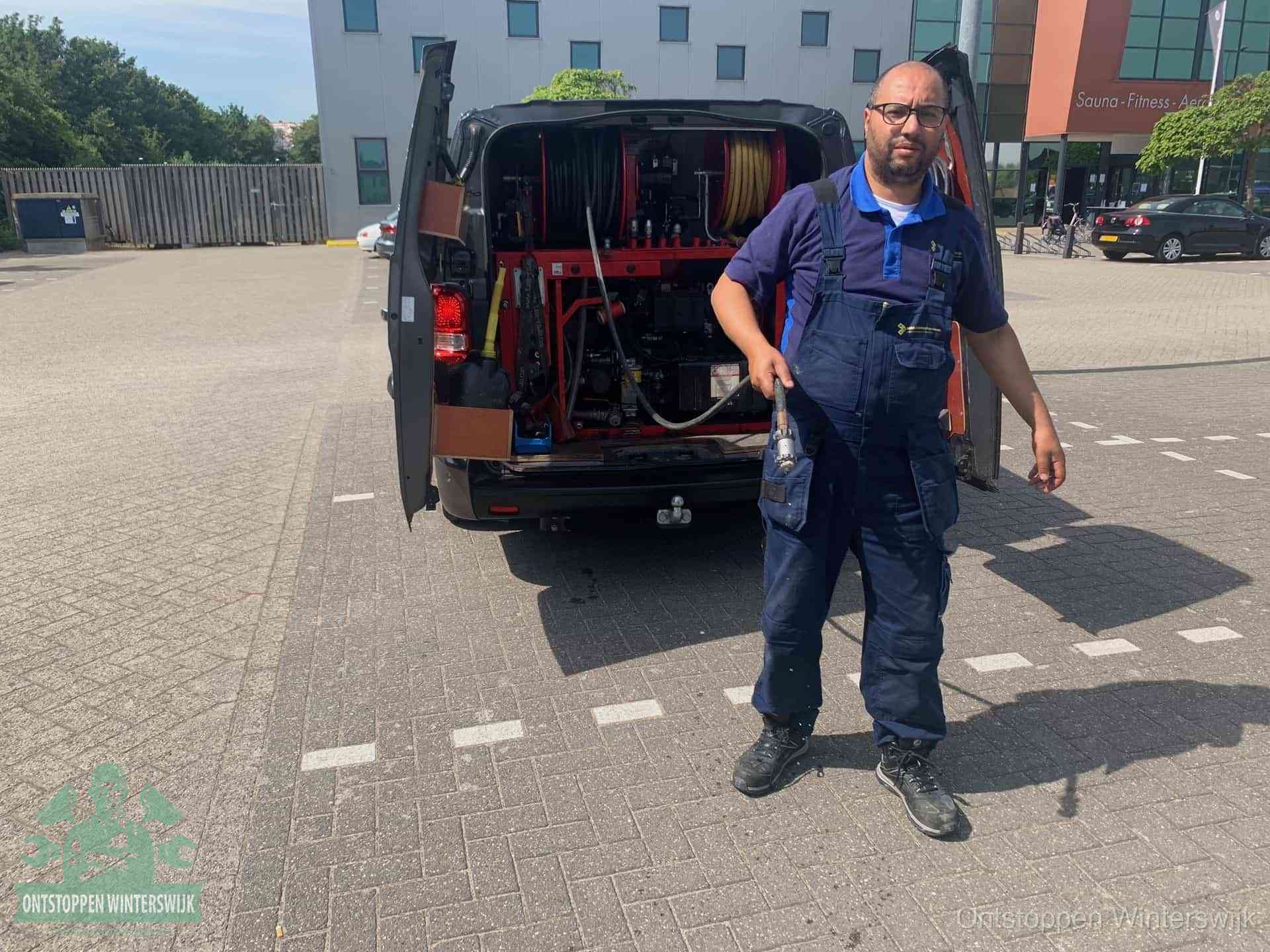 Een monteur bij zijn bestelbus met een hogedruk- en rioolreinigingsunit, klaar om de oorzaak van terugkerende wc-verstoppingen aan te pakken in Winterswijk